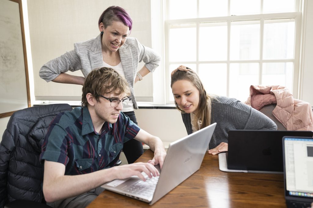 Woman with purple hair training users on a computer